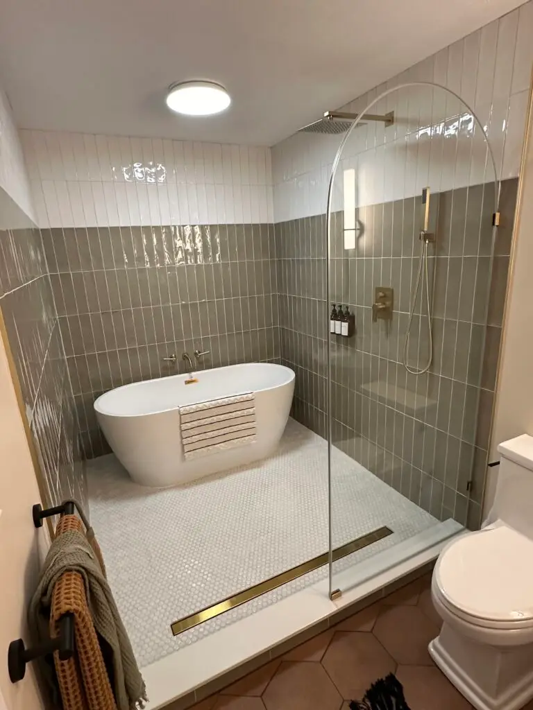 Finish basement contractors installing a modern bathroom with freestanding tub, glass walk-in shower, and custom tile work