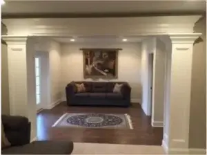Finished basement contractors in Pittsburgh create intentional living spaces like this one, designed by Pittsburgh Basement Finishing, with custom craftsman columns, crown molding, hardwood flooring, and a cozy seating area.